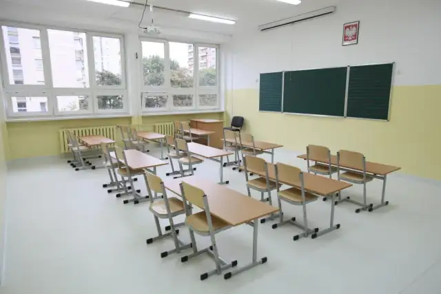 Pusta sala lekcyjna z ławkami i krzesłami, jakby czekająca na uczniów, kiedy wprowadzono gimnazjum w Polsce.