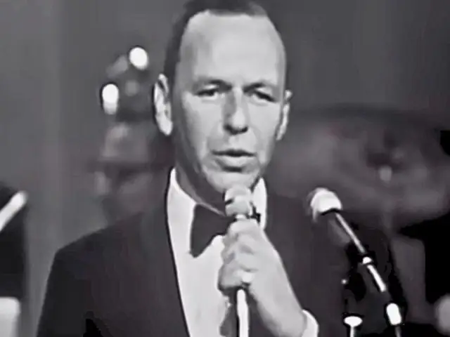 Frank Sinatra śpiewa "Fly Me to the Moon lyrics", ubrany w smoking.