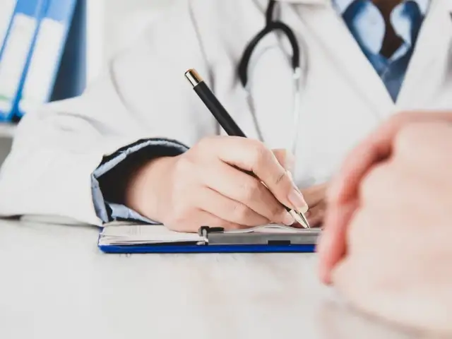 Lekarz pisze receptę, zastanawiając się, czy zwolnienie od psychiatry zostaje w papierach.