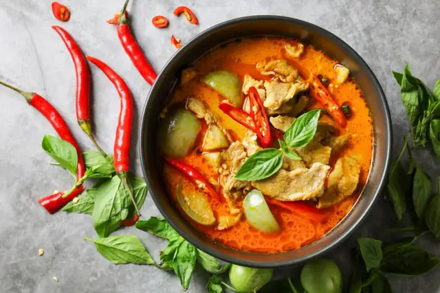 Miseczka czerwonego curry z mięsem, warzywami, papryczkami chili i bazylią.