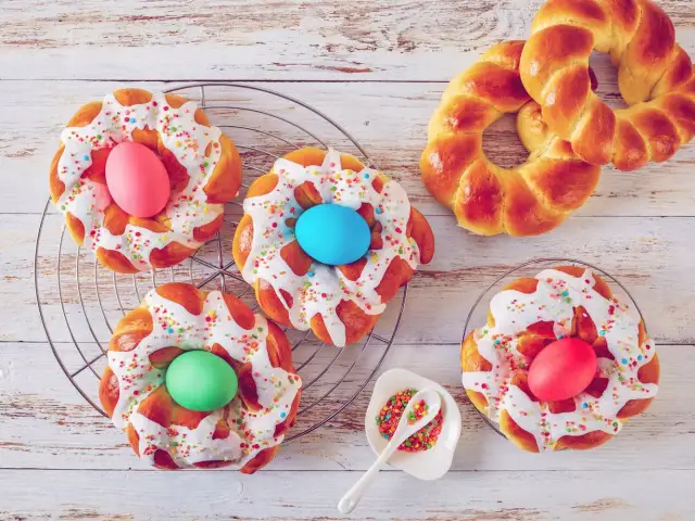 Bunte Osternester backen: Hefezöpfe mit Zuckerguss, Streuseln und gefärbten Eiern.