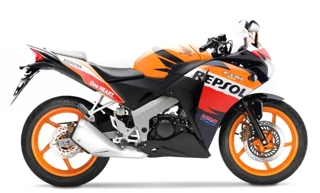 Pomarańczowo-czarny motocykl Honda CBR 125R w barwach Repsol, gotowy do jazdy z mocą V-max.
