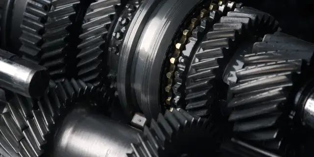 Zbliżenie na metalowe koła zębate, sugerujące awarię skrzyni biegów. Widoczne elementy mechanizmu, gotowe do naprawy.