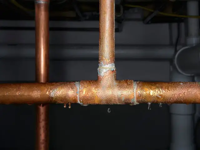 Gotitas de condensación cubren tuberías de cobre, indicando la necesidad de reparar la tubería.