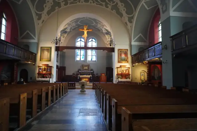 Wnętrze kościoła z ławkami, ołtarzem i krzyżem.