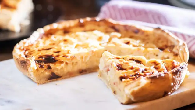 Ein köstliches Quiche Rezept, goldbraun gebacken, mit einem Stück zum Probieren.