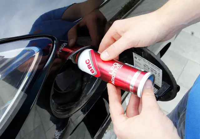 Ręce wlewają dodatek do LPG z puszki BRC do baku samochodu, dbając o czyszczenie wtrysków lpg.