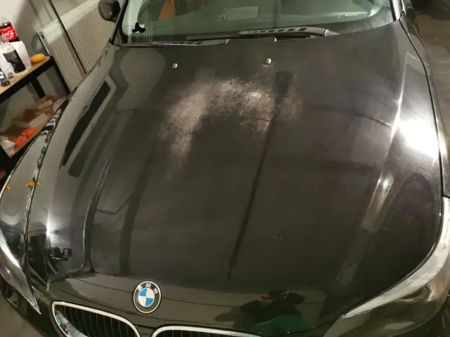 Na czarnej masce BMW widać liczne drobne rysy i zmatowienia, tworzące efekt "oczek na lakierze".