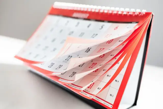 Otwarty kalendarz biurkowy z przewracanymi kartkami, widoczne daty i dni tygodnia.