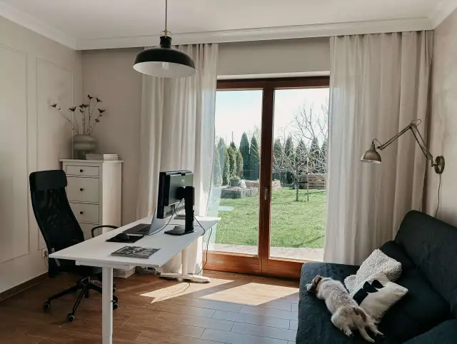 Jasne, oto propozycja:

Biuro z oknem przy ścianie i dyskretnym karniszem. Wygodne miejsce do pracy i odpoczynku, z widokiem na zielony ogród.