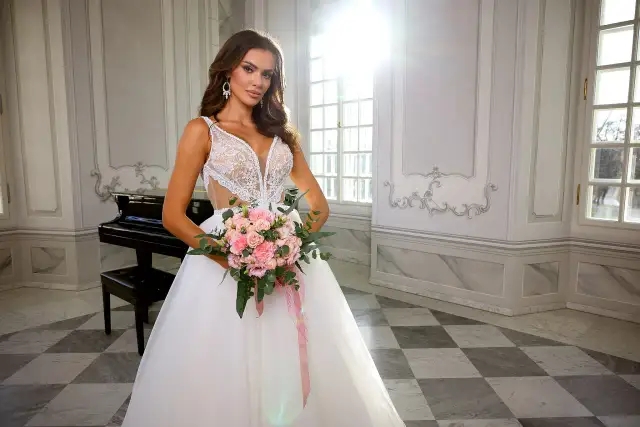 Panna młoda w sukni ślubnej z bukietem różowych kwiatów, w eleganckim wnętrzu z fortepianem.