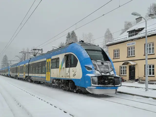 Niebiesko-biały pociąg Kolei Śląskich na stacji Wisła Głębce, od kiedy pociągiem do Wisły, w śnieżny dzień.