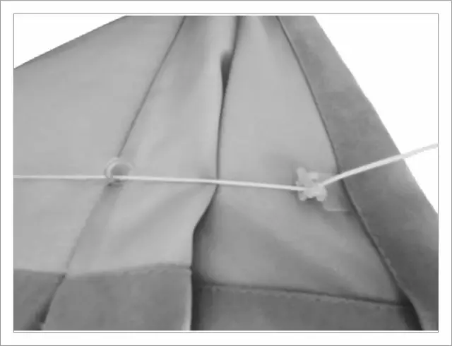 Szczegół mocowania sznurka do rolety rzymskiej na karnisz. Widoczne kółeczko i uchwyt.