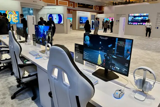 Stoisko gamingowe z fotelami, monitorami wyświetlającymi grę, klawiaturami i myszkami.