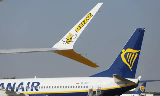 Dwa samoloty na płycie lotniska: jeden z logo Buzz i pszczółką, drugi z logo Ryanair. Czy to lot czarterowy a rejsowy?