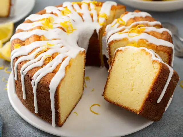 Szybka babka wilgotna, polana lukrem i posypana skórką cytrynową, kusi swoim apetycznym wyglądem.