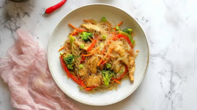 Pyszny makaron sojowy z kurczakiem i warzywami, jak od chińczyka. Danie wygląda apetycznie i kolorowo.