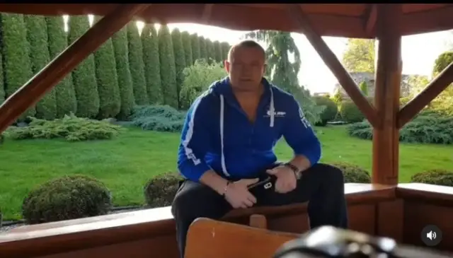 Mariusz Pudzianowski w swojej posiadłości, gdzie mieszka. W tle zadbany ogród z żywopłotem.