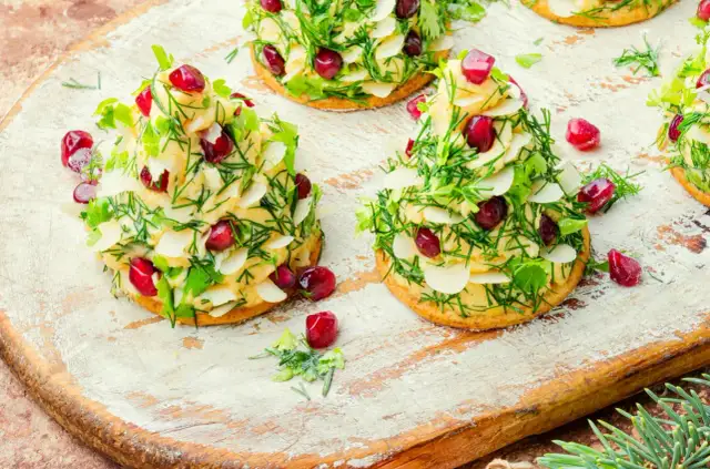 Urocze przekąski na święta w kształcie choinek, udekorowane kremem, ziołami, płatkami migdałów i granatem.