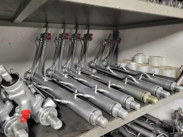 Rzędy srebrnych maglownic samochodowych z czerwonymi elementami na półkach magazynowych.