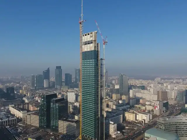 Varso Tower w budowie, z dźwigami na szczycie, góruje nad panoramą Warszawy. Trudno ocenić, ile pięter ma Varso Tower, ale jest to już najwyższy budynek w Polsce.