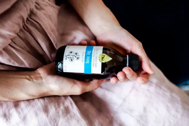 Dłonie trzymają butelkę oleju lnianego, idealnego do pielęgnacji twarzy. Naturalny, nierafinowany, tłoczony na zimno.