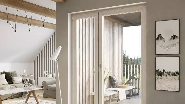 Jasne drzwi balkonowe w kolorze dąb bielony otwierają widok na taras z widokiem na las. W salonie przytulna kanapa i fotel.