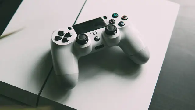 Biały kontroler PlayStation 4 leżący na konsoli PS4.