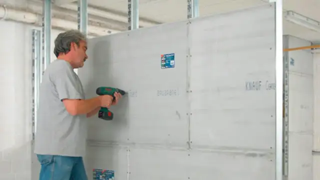 Mężczyzna przykręca płyty gipsowe do stelaża. Dowiedz się, jak kłaść płytki gipsowe dekoracyjne.