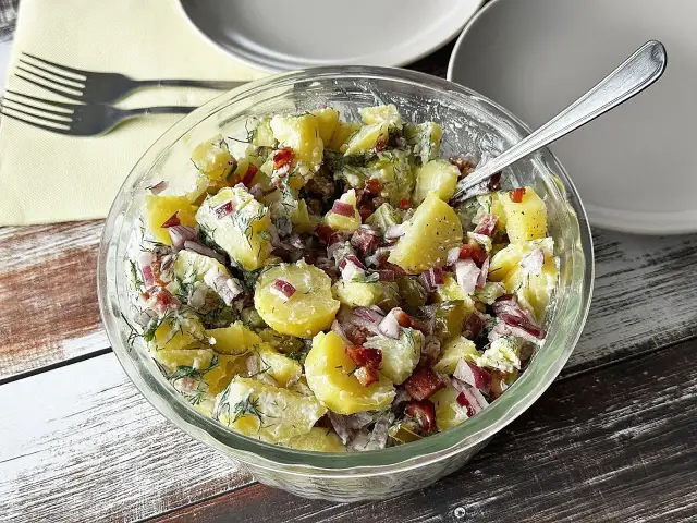 Pyszna sałatka ziemniaczana z boczkiem, cebulą i koperkiem w szklanej misie, gotowa do podania.