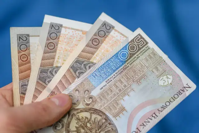 Dłoń trzyma polskie banknoty 200 zł i 500 zł. Chcesz wiedzieć, jak wypłacić pieniądze z funduszu inwestycyjnego Santander?