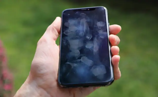 Dłoń trzyma smartfon z licznymi śladami palców na ekranie. Czy to efekt braku szkła hartowanego 9D?