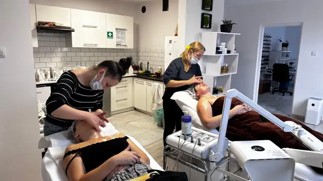 Uczestniczki szkoleń kosmetycznych ćwiczą masaż twarzy na leżących modelkach.