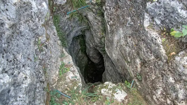 Głęboka szczelina skalna, wejście do jaskini. Wokół roślinność, jak w rezerwat przyrody węże.