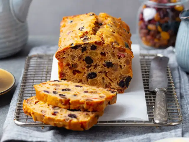 Pyszny keks Ani gotuje się w piekarniku, pełen bakalii. Pokrojone plastry kuszą aromatem.