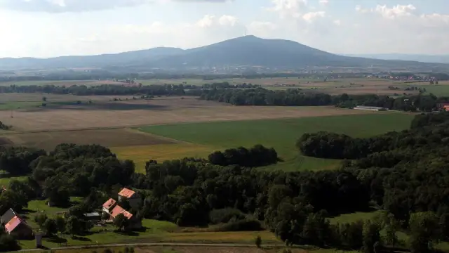 Widok na górzystą okolicę obok Wrocławia z polami, lasami i kilkoma domami.