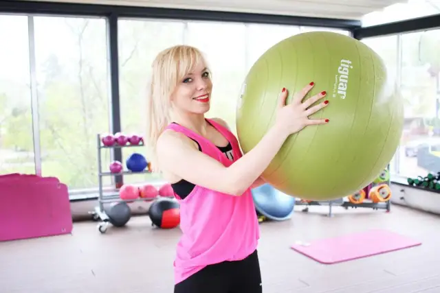 Uśmiechnięta blondynka z piłką gimnastyczną. Czy brzuch można ćwiczyć codziennie? Ona wie!