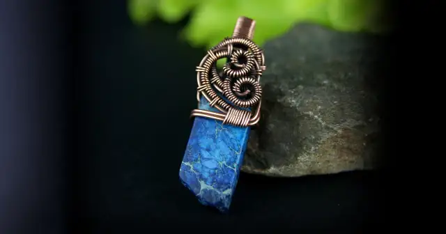 Wisior z niebieskim kamieniem i miedzianym drucianym owinięciem na kamieniu.