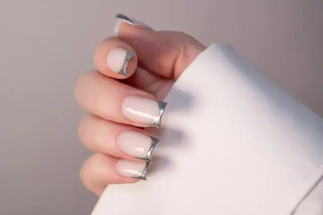 Dłonie z eleganckimi pazurkami french w metalicznym odcieniu.