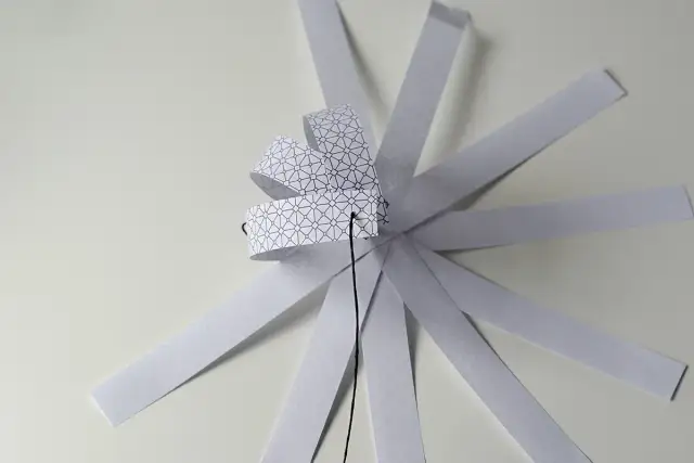 Papierowa ozdoba choinkowa 3D w trakcie tworzenia, z pasków z geometrycznym wzorem.