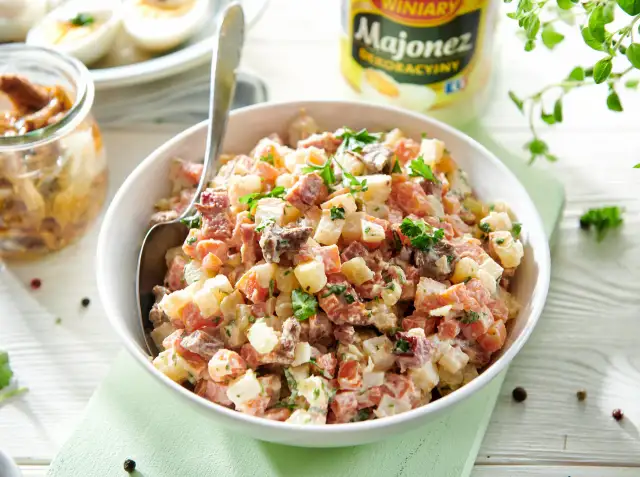 Pyszna sałatka z grzybkami marynowanymi, ziemniakami, jajkiem i majonezem, udekorowana natką pietruszki.