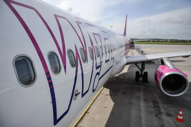 Samolot Wizzair, znanej firmy lotniczej, na płycie lotniska. Różowe logo i silnik.