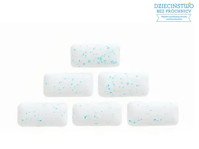 Białe gumy do żucia z niebieskimi drobinkami ułożone w piramidę. Żucie gumy pomaga zapobiegać próchnicy.