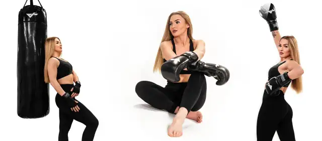 Kobieta w stroju sportowym i rękawicach bokserskich pozuje przy worku treningowym.