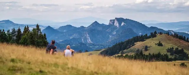 Para siedząca na trawiastym wzgórzu z widokiem na góry Pieniny.