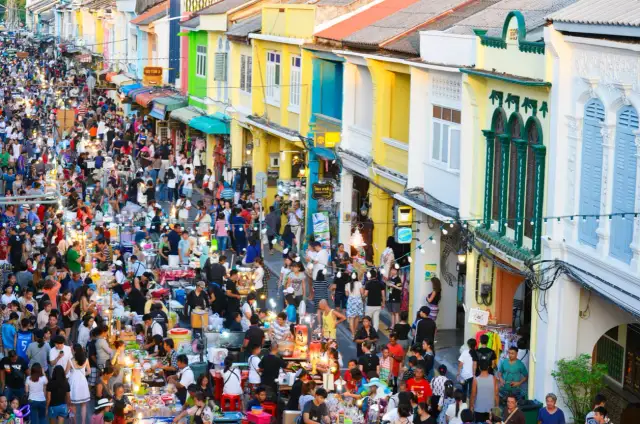 Tłoczny nocny targ w Phuket, pełen kolorowych budynków i ludzi. Idealne miejsce, by poczuć atmosferę i zastanowić się, phuket kiedy jechać.