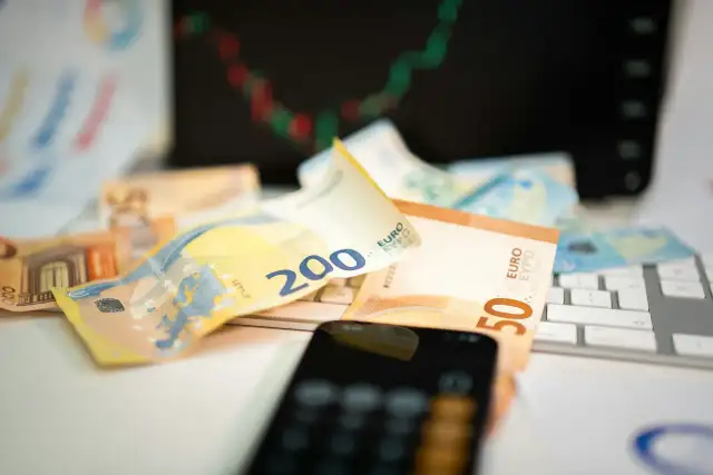 Euro banknoty na klawiaturze, telefon i wykres giełdowy sugerują inwestowanie w waluty.