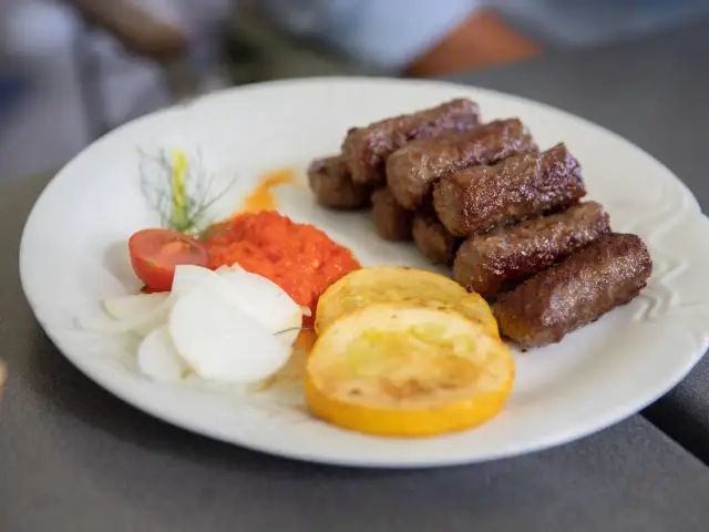 Cevapi, klasyka kuchni słoweńskiej, podane z ajvarem, cebulą i pomidorem.