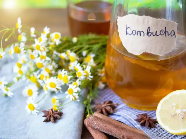 Szklany słój z kombuchą, cytryna, rumianek, cynamon i anyż.