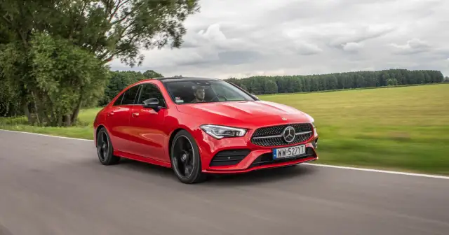 Czerwony Mercedes-Benz CLA Coupe pędzi po drodze wśród zielonych pól i drzew.